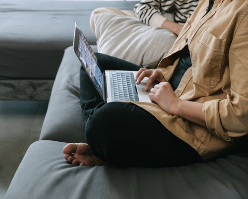 Person changing sitting posture while working on a laptop at home